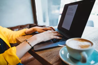 Was sind die besten Jobs für digitale Nomaden? : Berater für digitales Marketing bei einem Macbook Pro in einem Café mit einer Cappuccino-Kaffeetasse mit Latte Art.